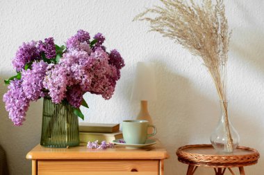 İçinde güzel leylak çiçekleri olan çekmeceler, oturma odasında masa ve otlar, yakın plan.