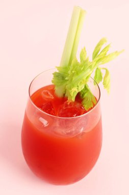 Pembe arka planda kerevizli bir bardak Bloody Mary.