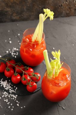 Gri masadaki domatesli ve kerevizli Bloody Mary bardakları