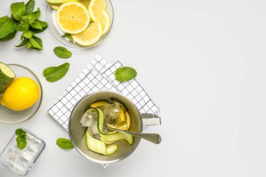 Beyaz zemin üzerinde salatalık limonatası hazırlamak için malzemelerle dolu kova ve kaseler.