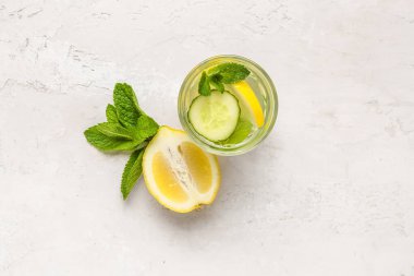 Beyaz arka planda salatalık ve nane aromalı bir bardak limonata.