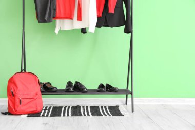 Askıda asılı şık okul üniforması, sırt çantası ve ayakkabılar yeşil duvarın yanında