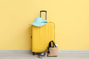 Pasaportlu bavul, bilet ve sarı arka planda plaj aksesuarları. Seyahat kavramı
