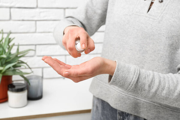 Woman applying sanitizer on her hands at home, closeup