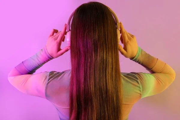 ヘッドフォンの若い女性は色の背景で音楽を聴く — ストック写真