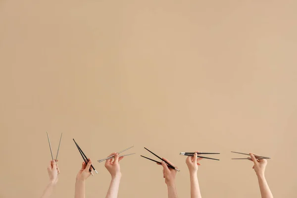 Kadın Erkek Elleri Kahverengi Arka Planda Farklı Yemek Çubukları Tutuyor — Stok fotoğraf