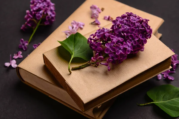 stock image Beautiful lilac flowers and books on dark background, closeup