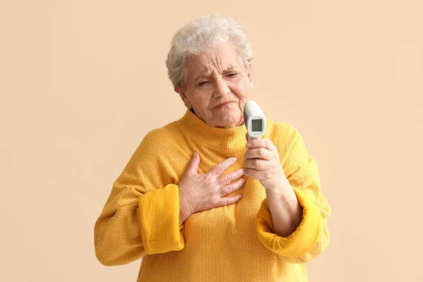 Irriterande Senior Kvinna Med Infraröd Termometer Beige Bakgrund — Stockfoto