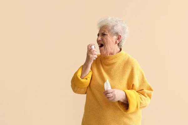 Ill Senior Woman Spray Sore Throat Beige Background — Stock Photo, Image