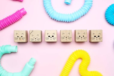 Pembe arka planda çizilmiş kedi ifadeleri olan tahta küpler.