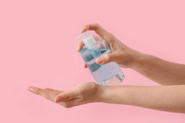 Pembe arka planda sıvı sabun olan eller