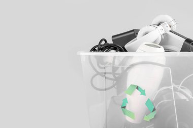 Gri arka planda farklı ev aletleri olan geri dönüşüm kutusu