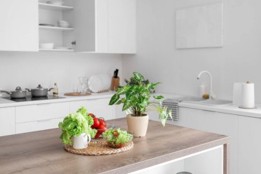 Modern mutfakta taze sebzelerle ahşap ada masası.