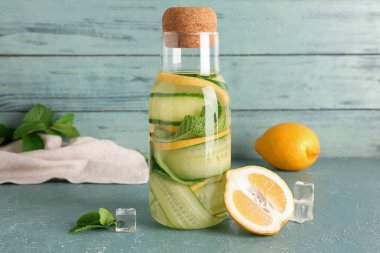 Mavi masada bir şişe salatalık ve naneli limonata.