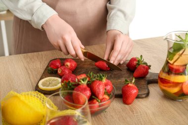 Mutfakta limonata için çilek kesen bir kadın.