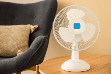 Oturma odasının içinde modern elektrikli vantilatör olan ahşap bir sehpa.