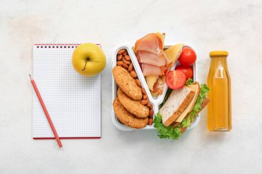 Kırtasiye malzemesi, içecek ve beslenme çantası ve hafif arka planda lezzetli yemekler.