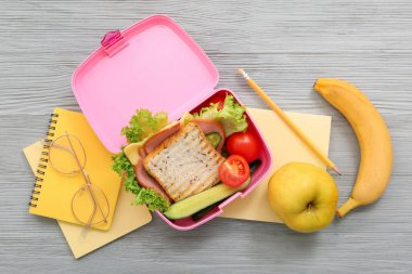 Kırtasiye malzemeleri, gözlükler ve gri ahşap arka planda lezzetli yemekler.