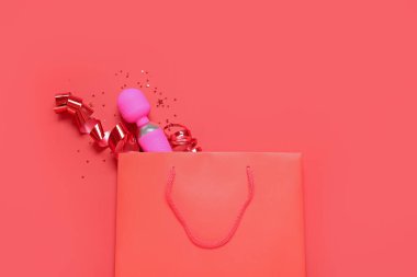 Kırmızı arka planda vibratör ve kurdeleli alışveriş torbası.