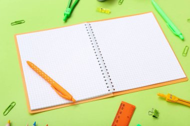 Boş defter ve yeşil arkaplanda farklı kırtasiye malzemeleri