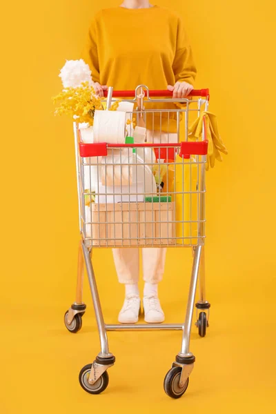 Vrouw Met Winkelwagen Vol Schoonmaakspullen Met Bloemen Gele Achtergrond — Stockfoto