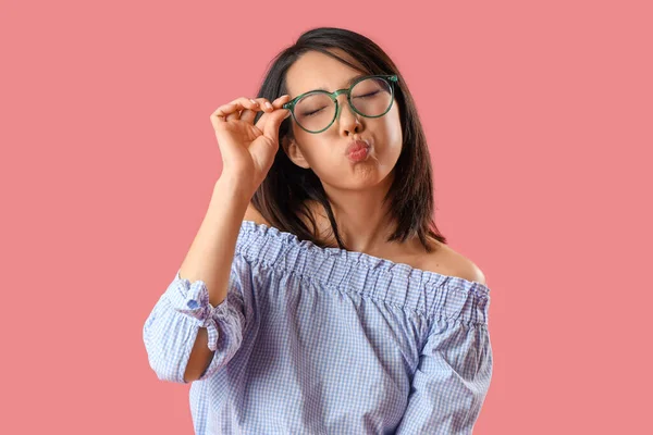 漂亮的亚洲女人戴着时髦的眼镜 在粉色的背景上飞吻着 — 图库照片