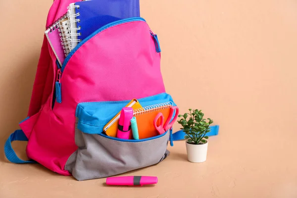 米色墙边桌子上贴有笔记本 家居用品和标识的彩色学校背包 — 图库照片