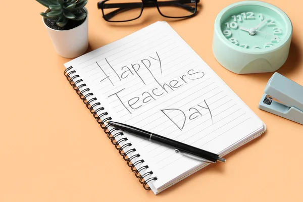 Notebook with text HAPPY TEACHERS DAY, alarm clock and eyeglasses on orange background