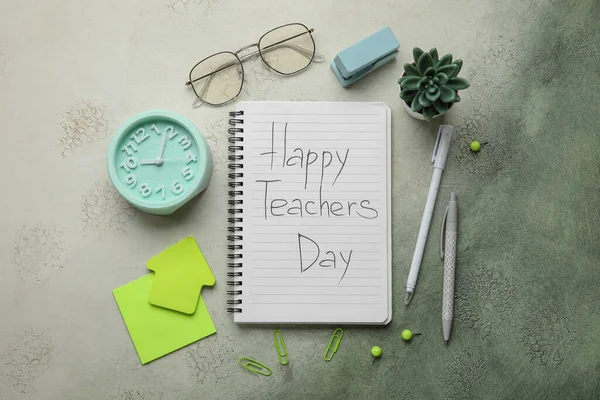 Notebooks with text HAPPY TEACHERS DAY, alarm clock and different stationery on grunge green gradient background