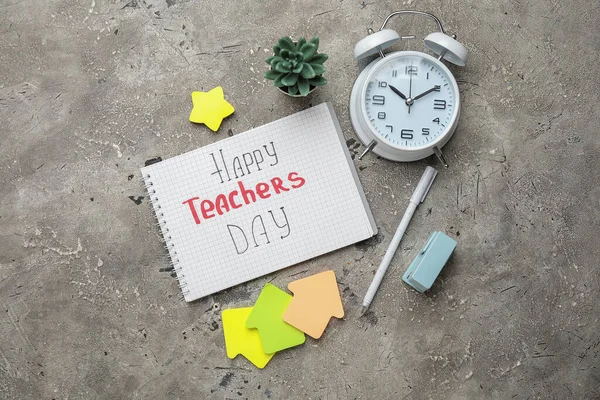 Notebook with text HAPPY TEACHERS DAY, alarm clock and different stationery on grunge grey background