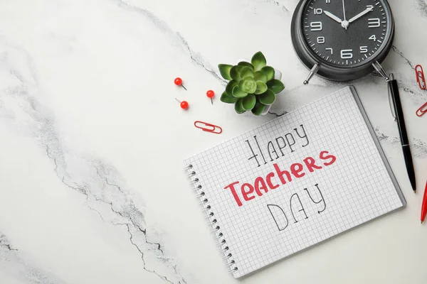 Notebook with text HAPPY TEACHERS DAY, alarm clock and pens on grunge white background