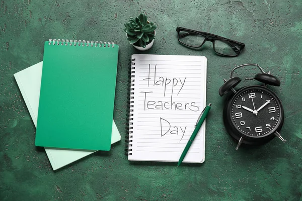Notebooks with text HAPPY TEACHERS DAY, alarm clock and eyeglasses on grunge green background