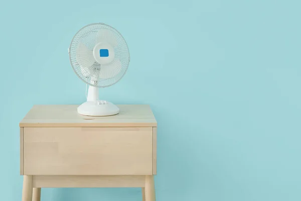Houten Tafel Met Moderne Elektrische Ventilator Nabij Blauwe Muur — Stockfoto