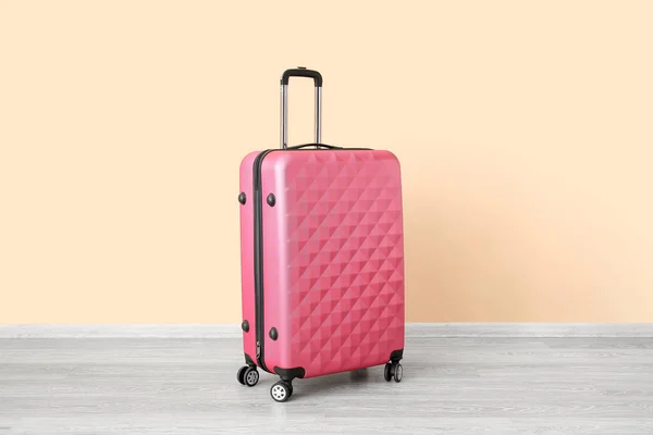 淡いオレンジの壁の近くのピンクのスーツケース 旅行のコンセプト — ストック写真
