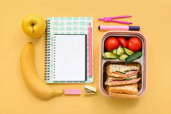 Verschiedene Schreibwaren Und Lunchbox Mit Leckerem Essen Auf Gelbem Hintergrund — Stockfoto