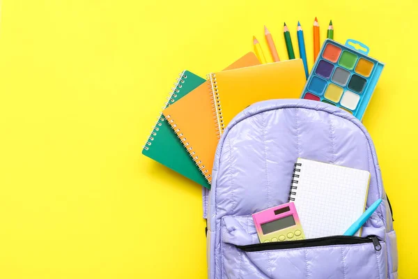 带有空白笔记本电脑和黄色背景的不同文具的背包 — 图库照片