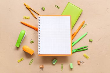Boş defter ve bej arkaplanda farklı kırtasiye malzemesi
