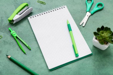 Kırtasiyeli boş defter ve grunge yeşil arka planda ev bitkisi