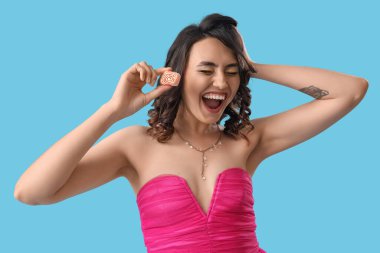 Mavi arka planda şekeri olan mutlu genç bir kadın.