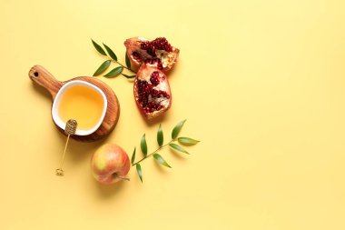 Sarı arka planda Rosh Hashanah kutlaması (Yahudi Yeni Yılı) için bir kase bal, nar ve elma içeren tahta tahta tahta tahta tahta tahta.