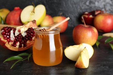 Rosh Hashanah kutlaması için kavanoz bal, nar ve elma (Yahudi Yeni Yılı) siyah masada