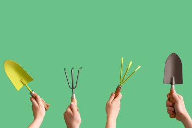 Bahçeyle uğraşan insanlar yeşil arka planda kürek ve tırmık taşıyorlar.