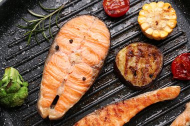 Kızartma tavasında ızgara somon bifteği ve sebzeler, yakın plan.