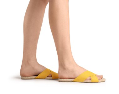 Beyaz arka planda parmak arası terlik giymiş kadın bacakları