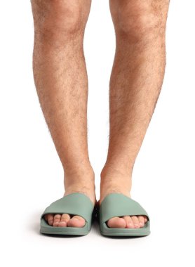 Beyaz arka planda parmak arası terlik giymiş erkek bacakları