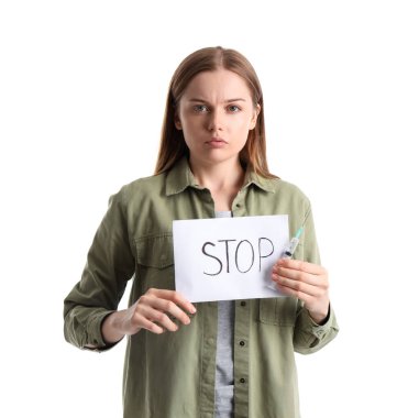 Beyaz arka planda dur yazan şırınga ve kağıt tutan genç bir kadın keş.