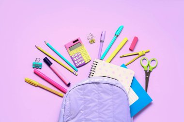 Hesap makineli sırt çantası ve leylak arkaplan üzerinde farklı kırtasiye malzemesi