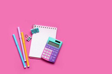 Pembe zemin üzerinde kırtasiye malzemesi olan modern hesap makinesi