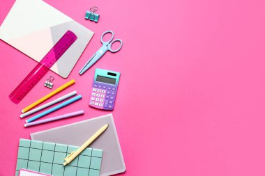 Pembe zemin üzerinde kırtasiye malzemesi olan modern hesap makinesi