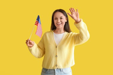 Sarı arka planda Amerikan bayrağı olan mutlu genç kadın.